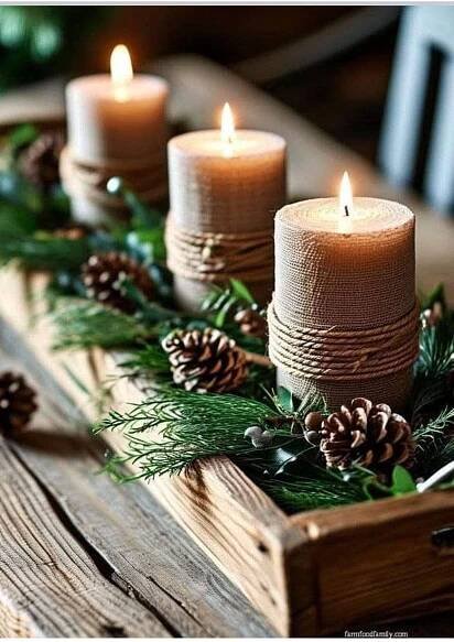 three lit candles are sitting in a wooden box with pine cones and evergreen branches on it