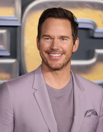Chris Pratt smiling in a lavender purple suit and shirt