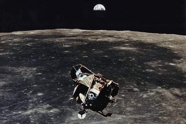 Apollo 11 ascent stage aloft above Earth with the moon rising in the distance