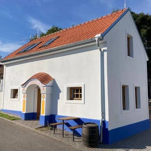 a small white building with a bench in front at Pod vinohradem - apartmány & vinné sklepy in Mutěnice