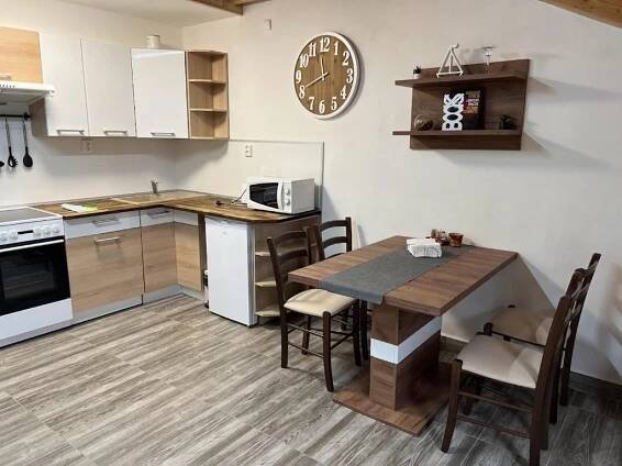 a kitchen with a table and a clock on the wall at Apartmány Nová duha Vavřinec in Vavřinec