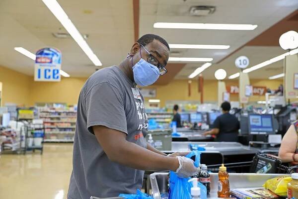 Joseph Vernon Smith, a Black man, bagging groceries at Giant Eagle. He’s wearing a face mask and his head is turned to look straight at the camera.