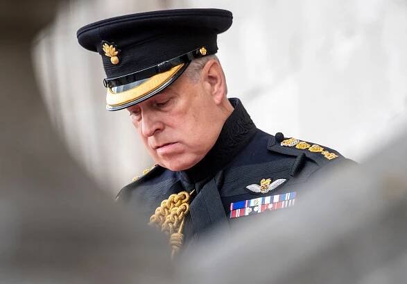 Prince Andrew in military uniform looks down solemnly.