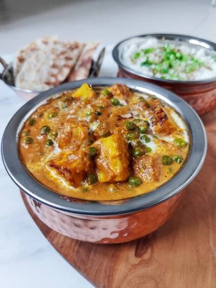 podávanie matar paneer v indických miskách, v pozadí miska ryže a placka paratha