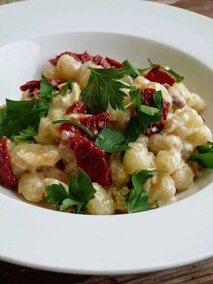 a white bowl filled with pasta and garnished with parsley