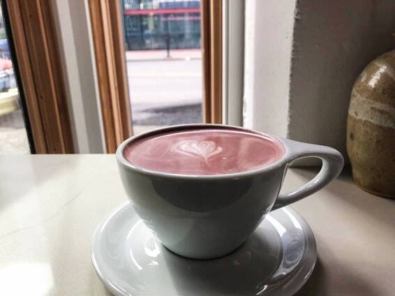 A cup of purple ube latte served in Hood Famous