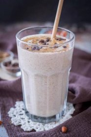 Peanut Butter Protein Shake in a glass topped with peanut butter and chocolate served with a straw