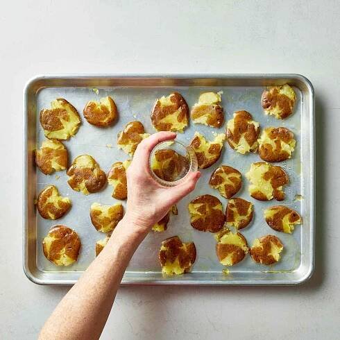 an image of the potatoes being smashed using a glass