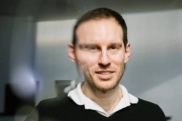 Alessio Figalli is seen slightly distorted through a refraction of eyeglasses in a classroom of the Institute for Advanced Study.