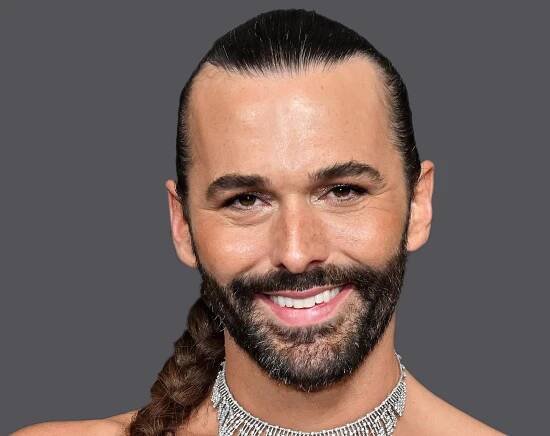 Jonathan Van Ness smiling in front of a grey background