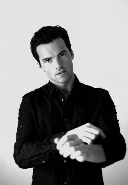 a black and white photo of a man with his hands folded out in front of him