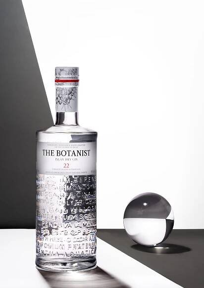 Still life of a bottle of Botanist Gin, with dramatic light and shadows going through the clear bottle and onto the white background.