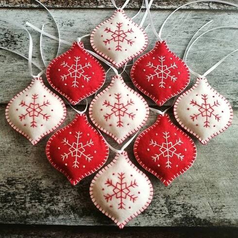 red and white ornaments hanging from strings on wooden surface with snowflakes in the middle