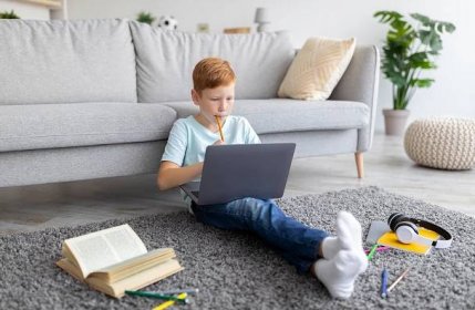Schooler ginger boy with laptop doing homework at home