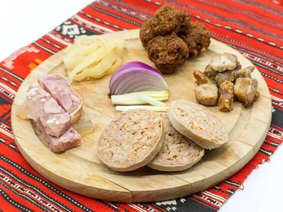 Tradiční vánoční plošina z různých vepřových předkrmů na tradiční červené látce — Stock obrázek