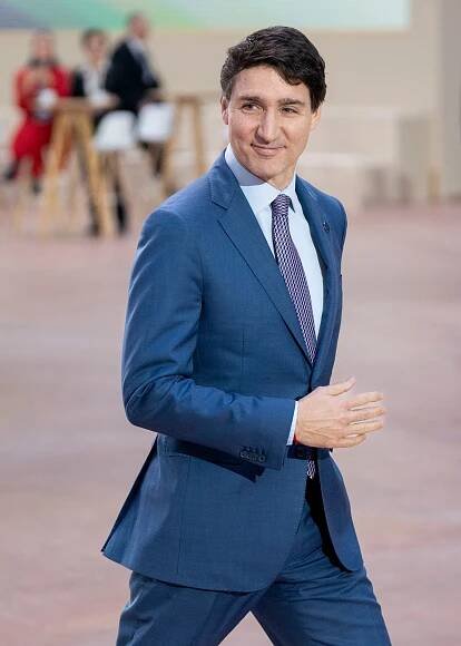 Person in a tailored suit walking at a formal event with others in the background