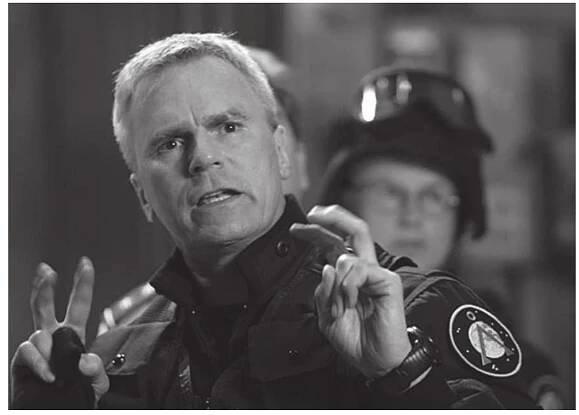 Jack O’Neill (Richard Dean Anderson) in one of his many “quotation” moments.  SG-1 who rings my bells. Unlike the darker, depressed, man-of-no: words version of O’Neil played by Kurt Russell in the movie, An: derson’s O’Neill may be a man of few words, but those that come out of his mouth are the kind you want to cryogenically freeze anc keep forever. The character O’Neill is paradigmatic of the reflexive intertextuality that’s integral to cult science fiction shows, both ir relation to the place of single episodes in relation to the series, anc in relation to the show’s overarching relationship to other example: of popular culture (consider O’Neill’s relentless references to Th Simpsons)*. Early on in Stargate SG-1, O'Neill reflexively points ou his character’s (and, by extension, the TV series’) point of differ ence to the Stargate film by clarifying how his name is spelt: “That’ O’Neill with two Ls. There’s another Colonel O’Neil with only ons L, he has no sense of humor at all” (2.9). My love of O’Neill comes firstly, from my understanding of his difference to the ‘other’ Star gate O’Neil and, secondly, from my memory’s collection and recol lection of special O’Neill performances that have become an inter textual sub-world within the Stargate universe. O’Neill’s magic i: especially to be found in his mastery of witty and pithy exchange: with other characters. Some examples: 