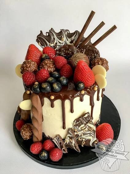 a cake with chocolate, strawberries and other toppings