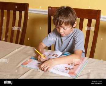 7 year old Mexican-American elementary school age boy does math homework using fingers to count at home Stock Photo