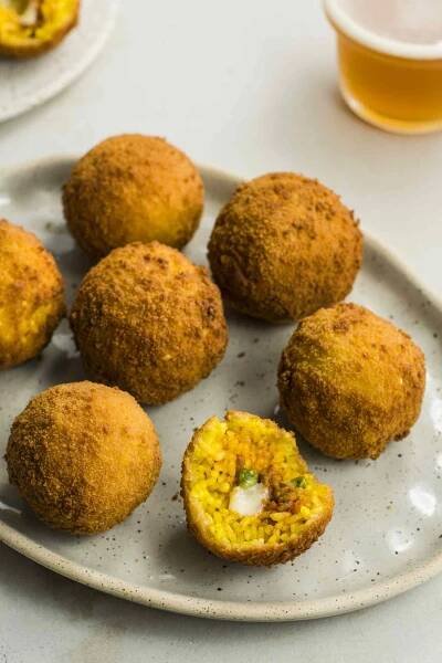 Classic Sicilian arancini rice balls, one with the inside filling exposed