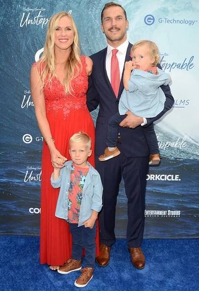 Bethany Hamilton went barefoot in a red floral-embroidered gown, while husband Adam Dirks wore brown dress shoes with a navy suit, and their sons matched in floral shirts and brown high-top sneakers at the Unstoppable premiere