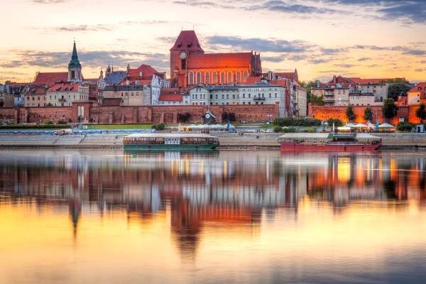 Staré město Toruň odráží v vistula řeky při západu slunce
