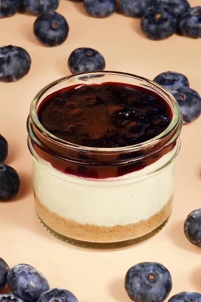 alt="Vanilla bean cheesecake jar with a classic graham cracker crust, topped with wild blueberry compote infused with honey and lime — made from scratch in San Antonio, Texas"