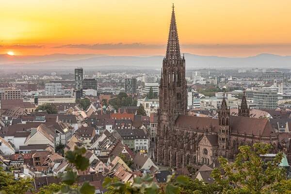 Blick von oben auf einen Sonnenuntergang hinter einer Stadt mit großem Münster