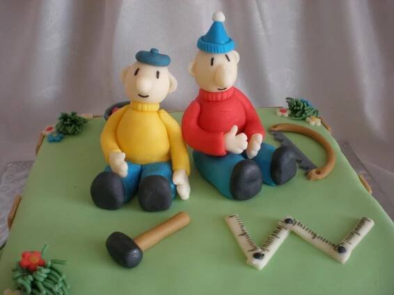 there is a cake that looks like two people sitting on top of a green surface