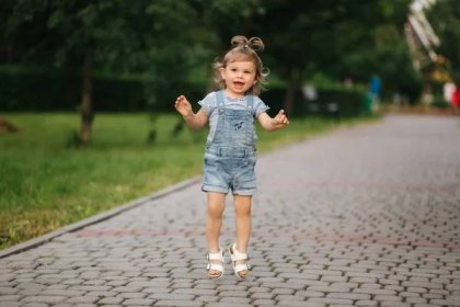 Roztomilé holčička osmnáct měsíců chůze v parku a skok — Stock fotografie