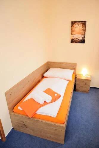 a bedroom with a wooden bed with two towels at Hotel Praha Potštejn in Potštejn