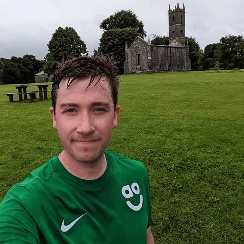 Ali McArthur wearing a green t-shirt in front of a castle. 