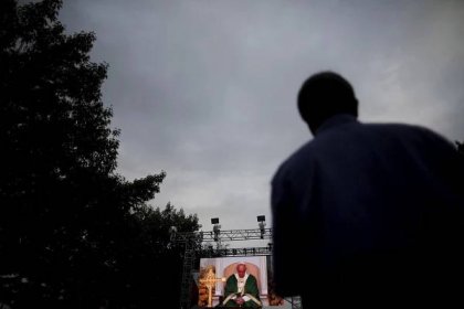 A man looks at a television screen showing Pope Francis taking a pause as he celebrates mass at the Festival of Families Sunday mass along Benjamin Franklin Parkway in Philadelphia, Pennsylvania