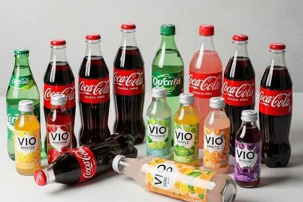 Verschiedene Flaschen mit Coca-Cola, Vio und anderen Getränken, die aufrecht und liegend auf einer hellen Fläche angeordnet sind. | PastaLab Hamburg