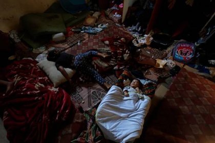 Yosra (L) and 2-month-old Ahmed Kuhail (R) sleep in their family home in the Sheikh Shaban cemetery.