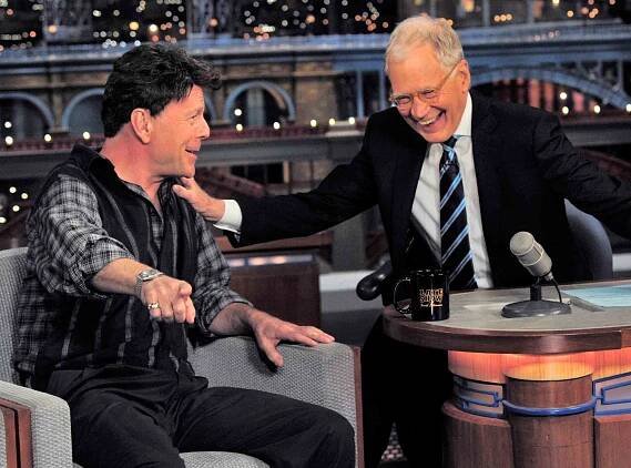 Bruce Willis, gets a laugh out of CBS Late Show host David Letterman as they look at TV monitor, by appearing dressed as he did 61 appearances ago on the show during April 22 taping in New York.