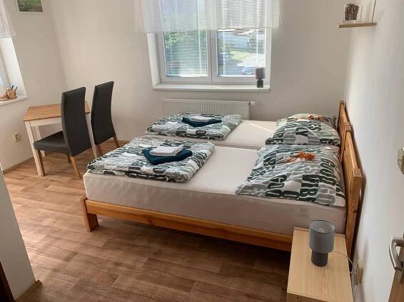 two beds in a small room with a table and chairs at Penzion Na Potoce in Ledeč nad Sázavou