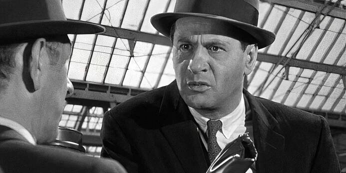 Eli Wallach looking at a man sitting in front of him in The Lineup (1958)