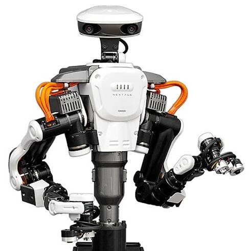 A white, black and orange human sized factory robot with two arms and a head with cameras.