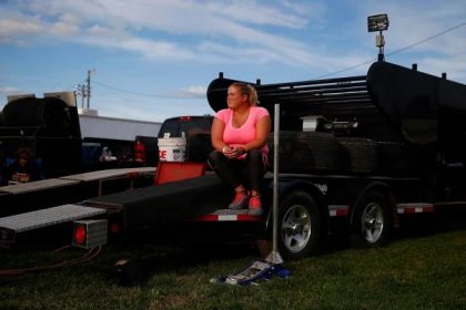 A woman sits on a race car trailer at the West Liberty Race Track.