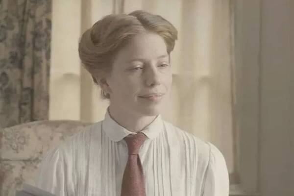 A woman in a white shirt looks serious 