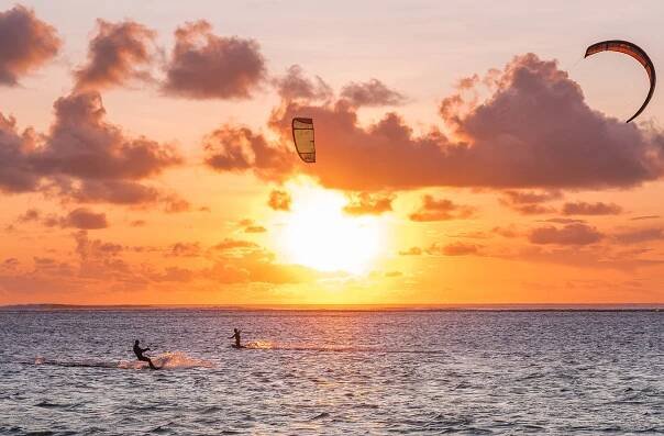 Sunset sky over the Indian Ocean bay with a kiteboarder riding kiteboard with a green bright power kite. Active sport people and beauty in Nature concept image. Le Morne beach, Mauritius — Stock obrázek