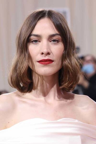 Alexa Chung wearing an off-the-shoulder ivory dress with red lipstick and her hair in a long bob