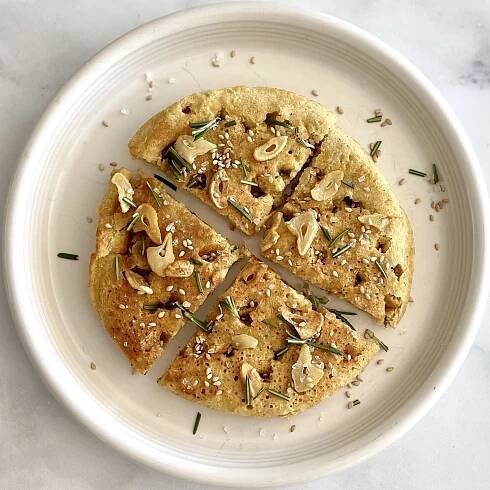 focaccia-style skillet chickpea flatbread, cut into wedges, on a white plate
