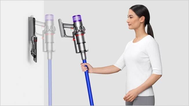 Woman placing Dyson V11™ vacuum into wall charging dock