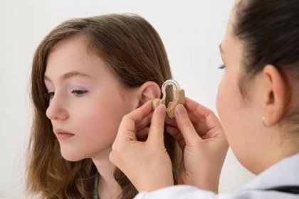 Doktor vložení sluchadla v uchu holka — Stock fotografie