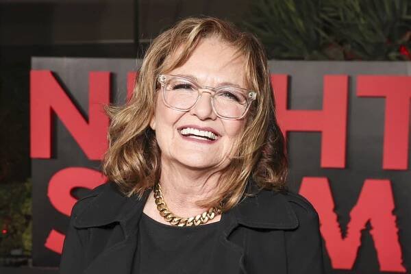 Nancy Lenehan smiling in front of a step and repeat.