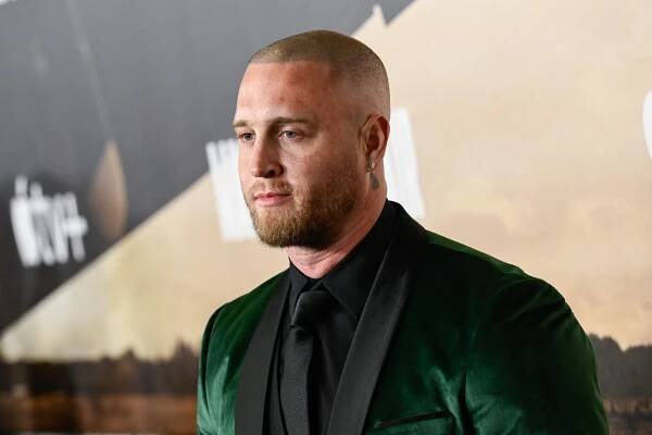 A portrait of Chet Hanks wearing a velvet green suit.