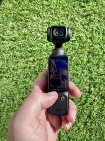 the dji osmo pocket 3 in a hand over artificial grass