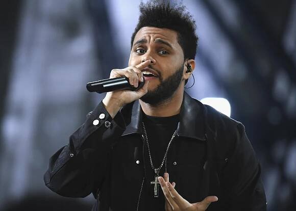 The Weeknd performs onstage in a black jacket.
